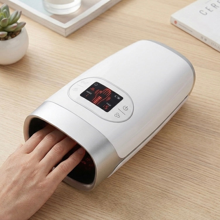 A hand massager with a digital display, shown with a hand placed inside the device on a wooden desk
